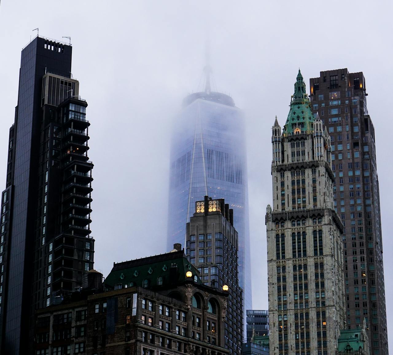 A dramatic view of New York City skyscrapers enveloped in fog, featuring iconic architecture.