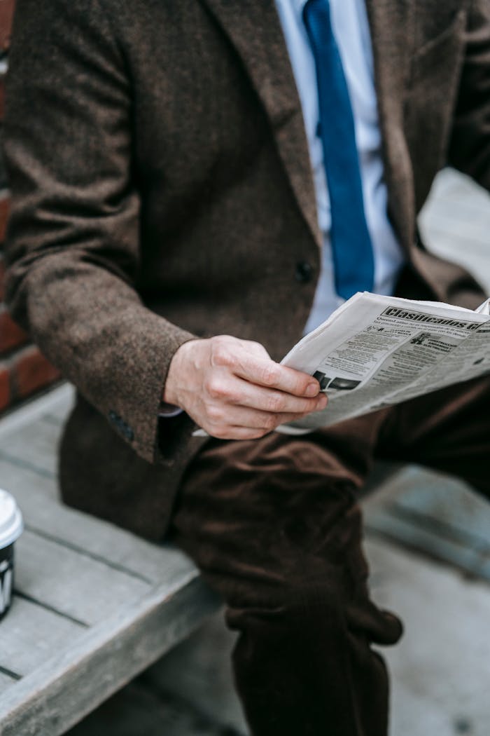 Business professional in brown suit reading newspaper outdoors. Urban style, winter fashion.